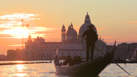 a gondola is rowed by a gondolier in front of the setting sun in romantic venice italy 2