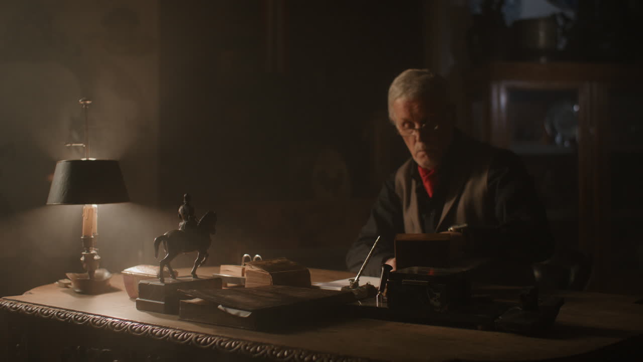 Older passionate man evaluates an old watch in his office at night