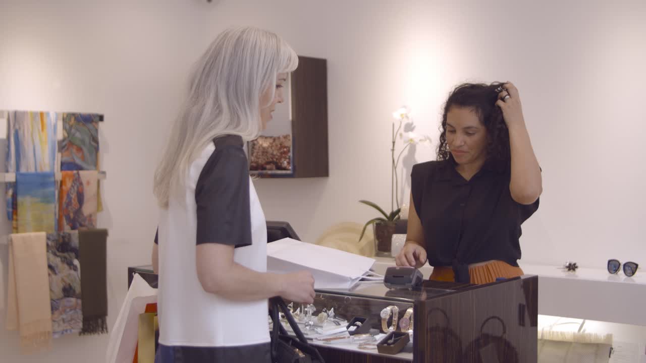 신용 카드로 구매 비용을 지불하는 행복한 공정한 머리 여자와 그녀에게 쇼핑백을 주는 점원