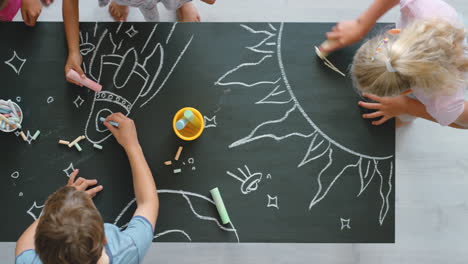 children drawing space scene on chalkboard