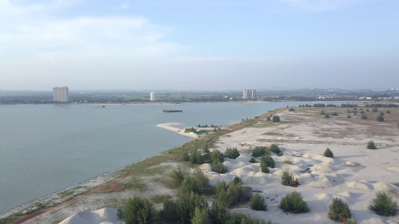 Beautiful panoramic view of the Melaka coastline, Malaysia, with white sand in the foreground and city buildings in the background