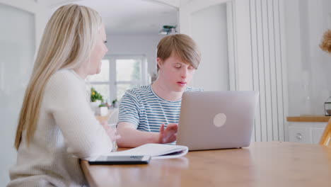 Mann-Mit-Down-Syndrom-Sitzt-Mit-Einer-Nachhilfelehrerin-Zusammen-Und-Nutzt-Laptop-Für-Den-Unterricht-Zu-Hause