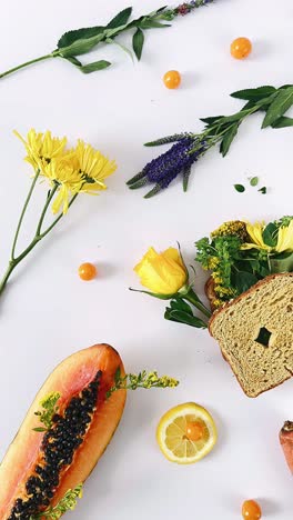colorful still life arrangement with flowers, fruit, and food