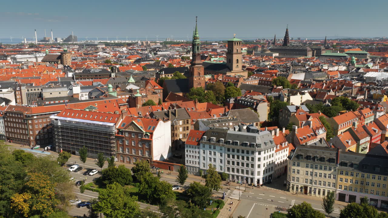 Dronebillede af historiske kirketårne, inklusive spir fra Nikolaj Kunsthal og tårnet fra Vor Frue Kirke i København, Danmark