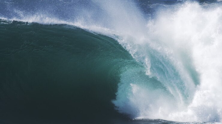 Cresting wave crashes with thick spray and white foam in crisp high speed motion