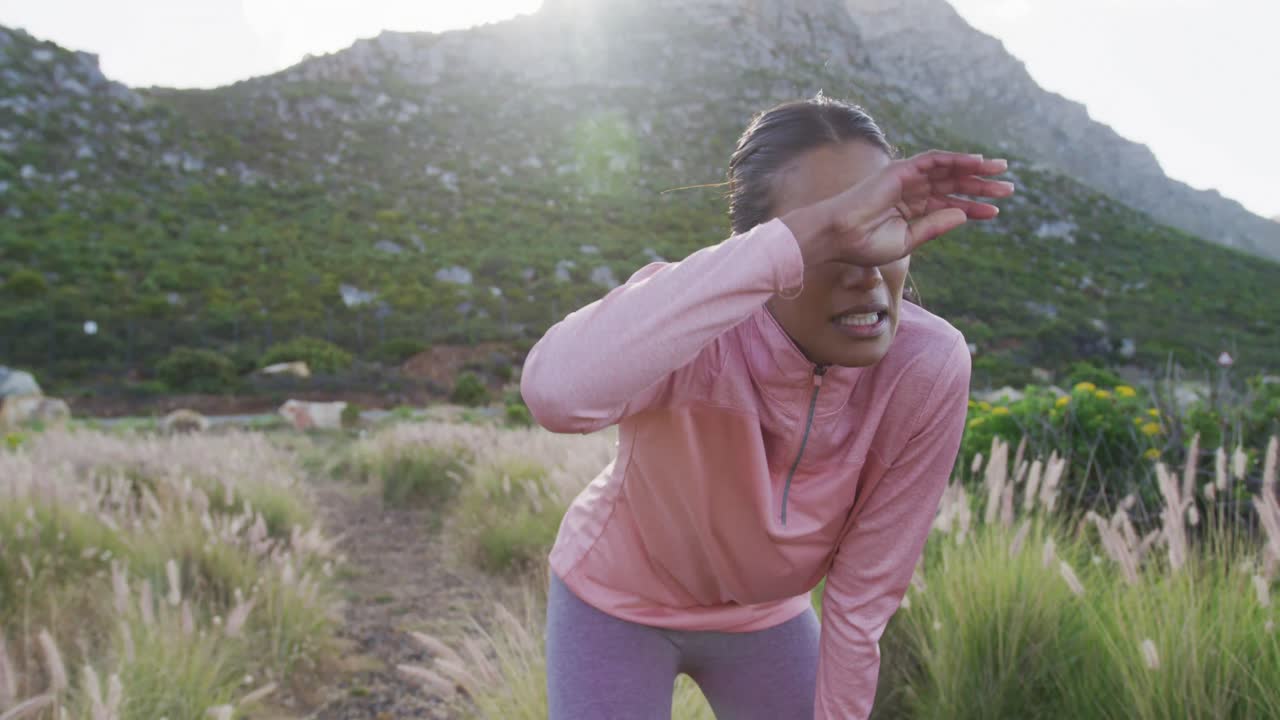 retrato de una mujer de raza mixta haciendo ejercicio descansando en un campo durante una carrera en el campo
