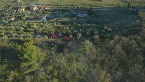 Toma-De-Drones-De-Bomberos-Rociando-Agua-Sobre-Olivos-En-Llamas-Con-Camiones-E-Hidrantes