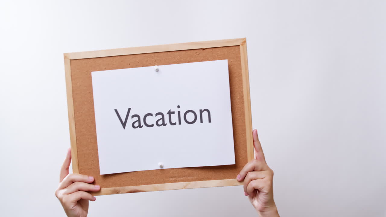 la mano de la mujer muestra el papel a bordo con la palabra vacaciones en un estudio blanco con espacio para copiar