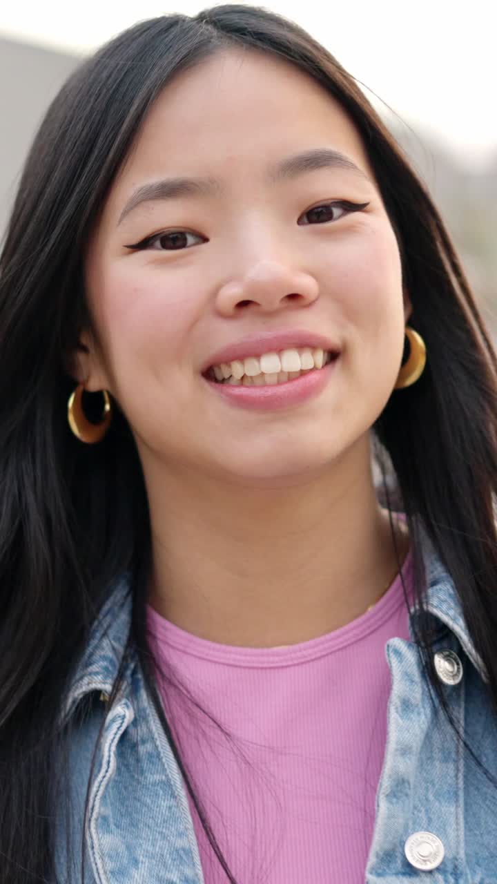 Asian young woman smiling at camera in the street