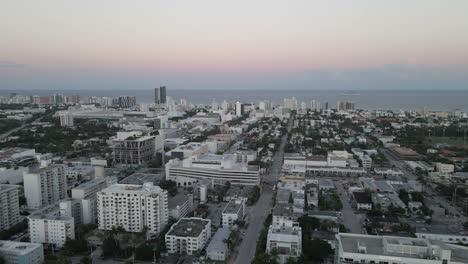dawn aerial pov follows street in south beach miami, atlantic beyond
