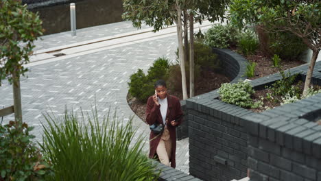 a woman walking down a city street talking on her phone.