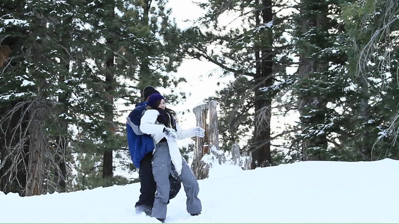 una pareja joven juega en la nieve
