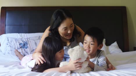 mother and kids playing with teddy bear in bedroom 4k