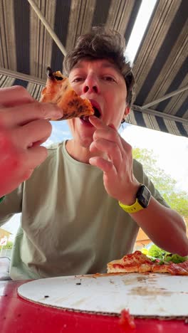 Un joven comiendo pizza.