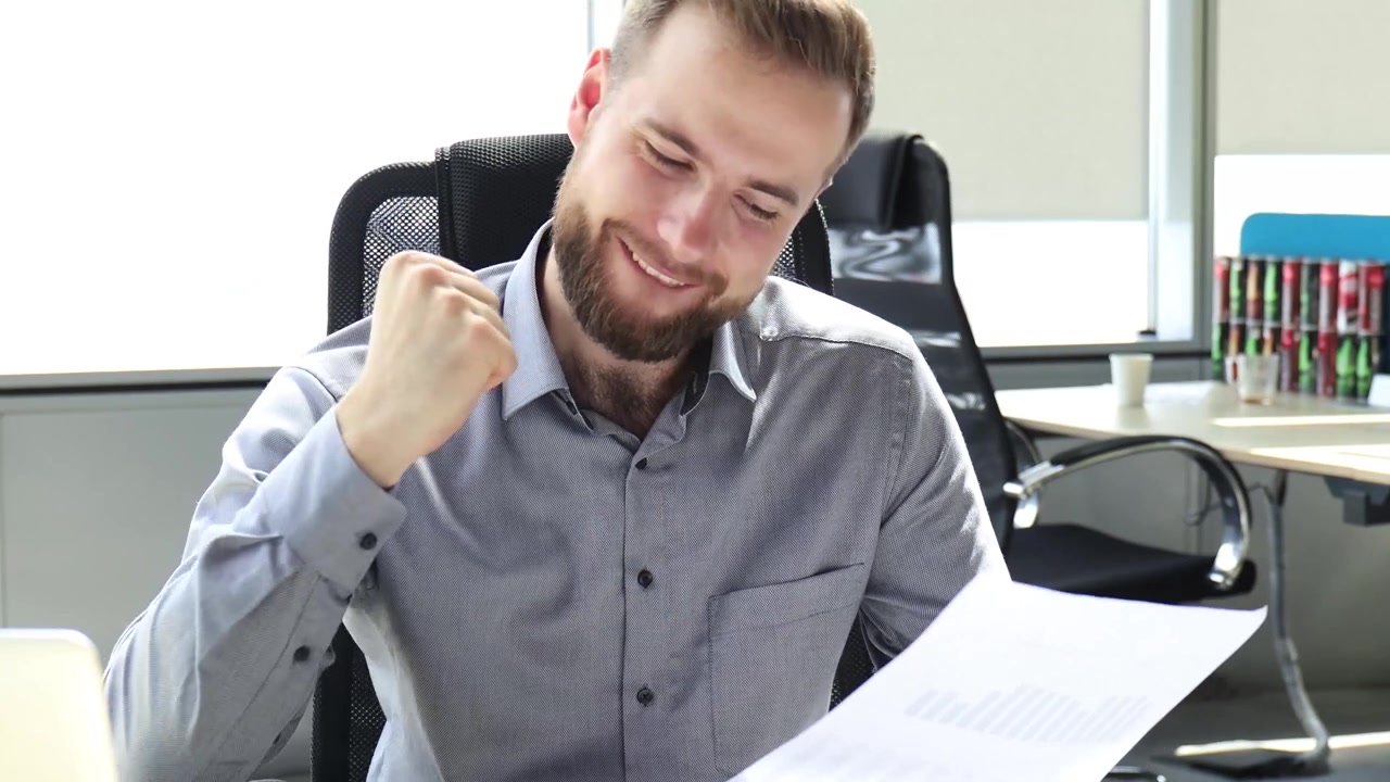 Satisfied Businessman Celebrates Success While Reading Document in Office