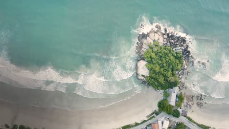 Beautiful-drone-cinematic-top-view-panning-over-the-rocks-of-the-ocean-on-a-brazilian-beach-with-white-sand-and-emerald-clear-water-at-sunrise