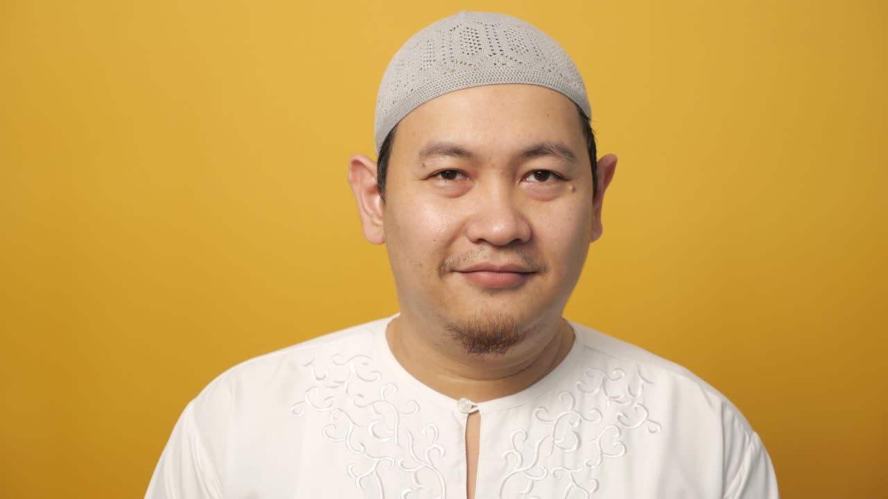 retrato de un joven musulmán asiático feliz sonriendo y posando para la cámara, contra el amarillo