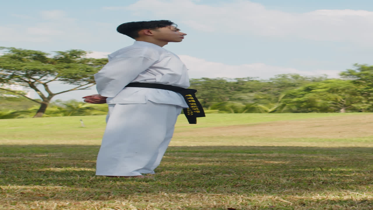 Sportsman in Dobok Bowing before Fight in Park