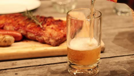 cerveza vertida en un vaso junto a las costillas de barbacoa