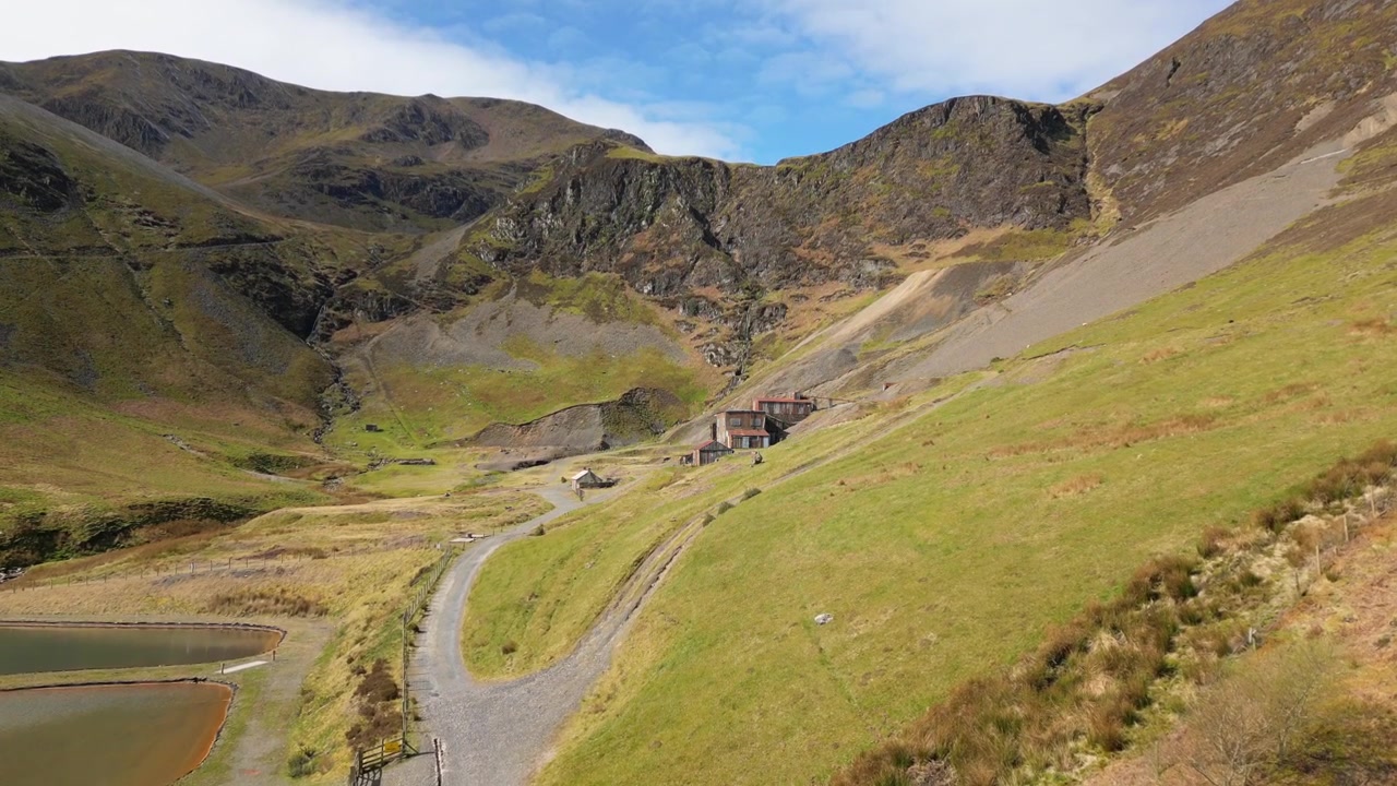 Turgåere på vei mot en forlatt gruve, med en stigning som avslører forfalne bygninger ved Coledale Beck i det engelske Lake District, Cumbria.