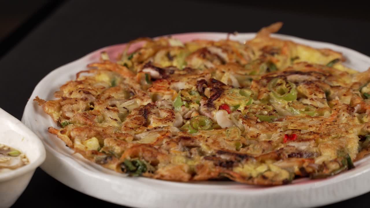 A crunchy seafood pancake with deep flavors, perfect with spicy soy sauce. 진한 풍미의 바삭한 해물전, 매콤한 간장 소스와 완벽한 조화.