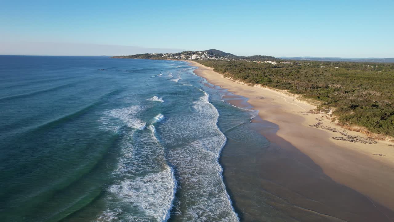 las olas del océano rodando hacia la playa de arena de coolum a lo largo del parque foreshore en queensland, australia