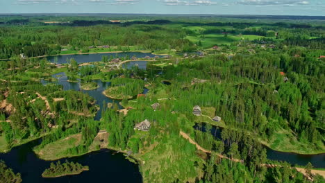 Casas-De-Vacaciones-Entre-Un-Bosque-Verde-Y-Pequeños-Lagos-En-Un-Parque-De-Vacaciones-Drone-Dolley-Tilt-Shot