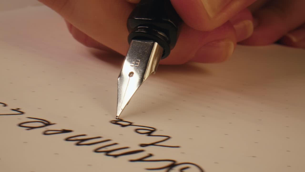 Primo piano di una mano che scrive con una penna stilografica su carta a pois