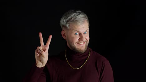 friendly stylish man feeling happiness, enjoyment, showing victory sign doing peace gesture, smiling