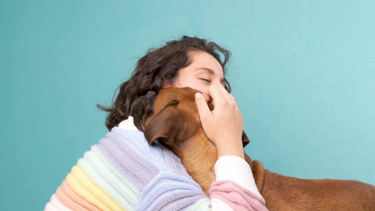 Woman stroking and hugging her boxer dog.