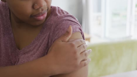 happy african american woman with bandage on her arm after vaccination