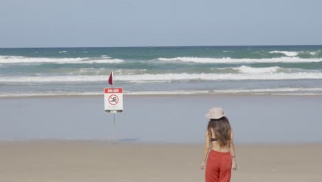 woman going to the beach, no swim danger red flag, agitated sea ocean