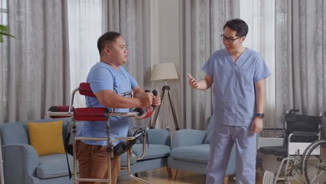 아시안 남성 간호사의 면 뷰는 커를 사용하는 환자에게 손을 흔들며 집에서 물리 치료를 할 때 손을 들어 축하합니다.