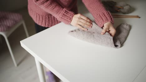 woman expecting baby looking at knitted sweater lying on table. handmade clothes