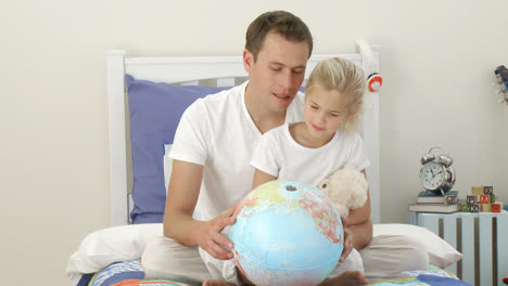 father and daughter looking at a terrestrial globe