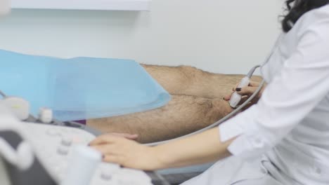 las manos de la mujer médico examinan la articulación de la rodilla del paciente joven utilizando un dispositivo de sensor de ultrasonido, sonografía. el médico ejecuta un sensor de ultrsonido sobre la pierna del paciente, la rodilla.
