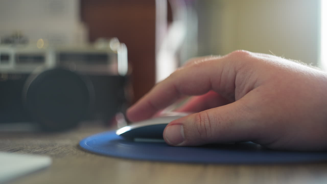 A caucasian man's hand clicking and dragging with a wireless mouse in his home office