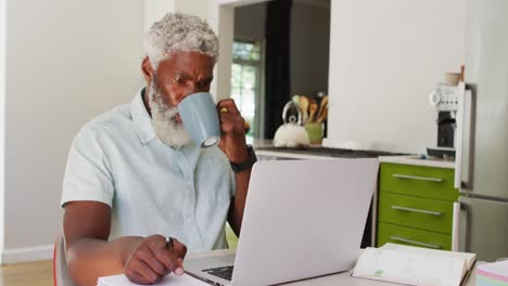 Afroamerikanischer-älterer-Mann,-Der-Kaffee-Trinkt-Und-Einen-Laptop-Benutzt