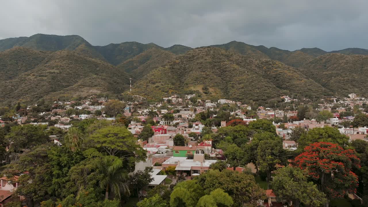 aéreo: drone volando sobre árboles y ciudad cerca de las montañas