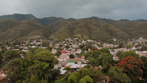 aéreo: drone volando sobre árboles y ciudad cerca de las montañas