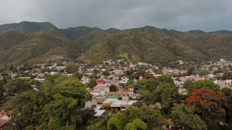 aerial: drone flying over trees and town near mountains