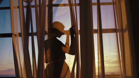 woman looking out window at sunrise/sunset