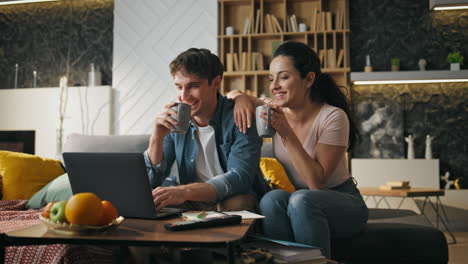 pareja riendo viendo una película en casa usando una computadora portátil. fin de semana familiar en un sofá acogedor