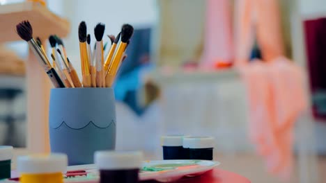 artist's brushes are in the bank, the paints are on the table near the easel. workplace in an art studio. circular motion cameras.