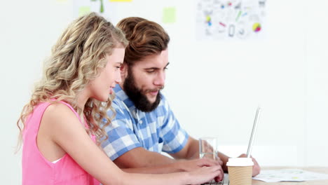 Smiling-casual-business-workers-using-laptop-together