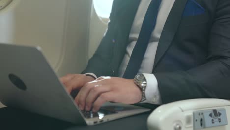 young businessman using laptop computer in airplane