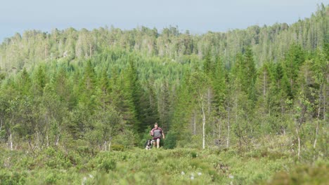 european man running and playing with pet alaskan malamute dog in the wilderness