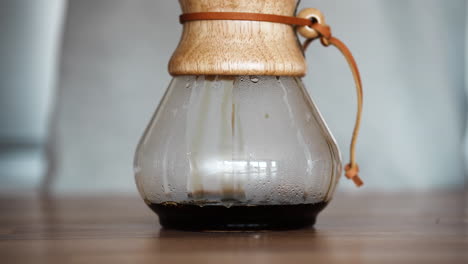 freshly brewed coffee dripping inside a pour over glass coffeemaker on the table