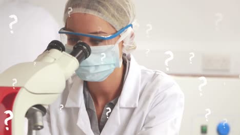 animación de signos de interrogación sobre una trabajadora de laboratorio caucásica con máscara facial usando un microscopio