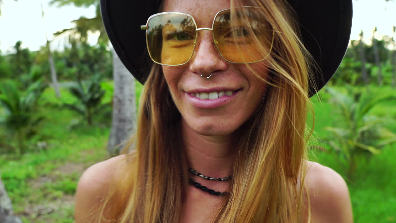 вид снизу на белокурую привлекательную женщину, идущую по джунглям с пальмами